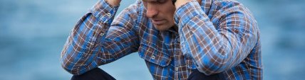 Hombre sentado al aire libre con las manos en la cabeza, agotado