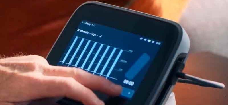 Mano ajustando el nivel de intensidad en la pantalla de la unidad BEMER