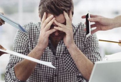Hombre con la cabeza entre las manos rodeado de compañeros que le entregan papeles