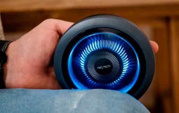 Mano sostiene un aplicador circular BEMER con anillo de luces azules encendido