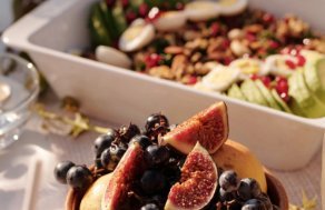 Plato con higos y uvas junto a una ensalada con granada y frutos secos