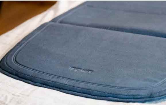 Primer plano de una esterilla textil azul marino acolchada sobre una sábana blanca