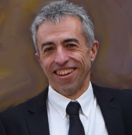 Hombre sonriente de pelo cano, con traje oscuro y corbata negra